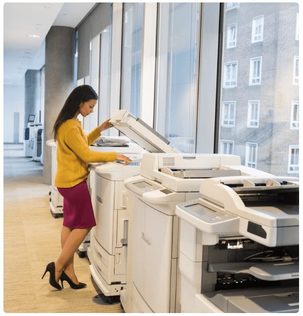 A woman standing next to an open printer.